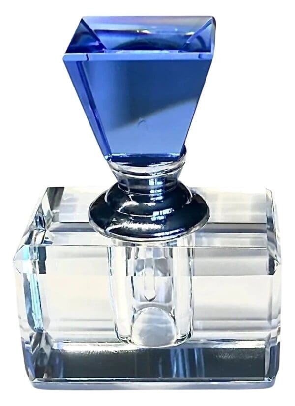 A blue glass bottle sitting on top of a clear block.