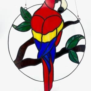 A stained glass parrot sitting on top of a tree branch.