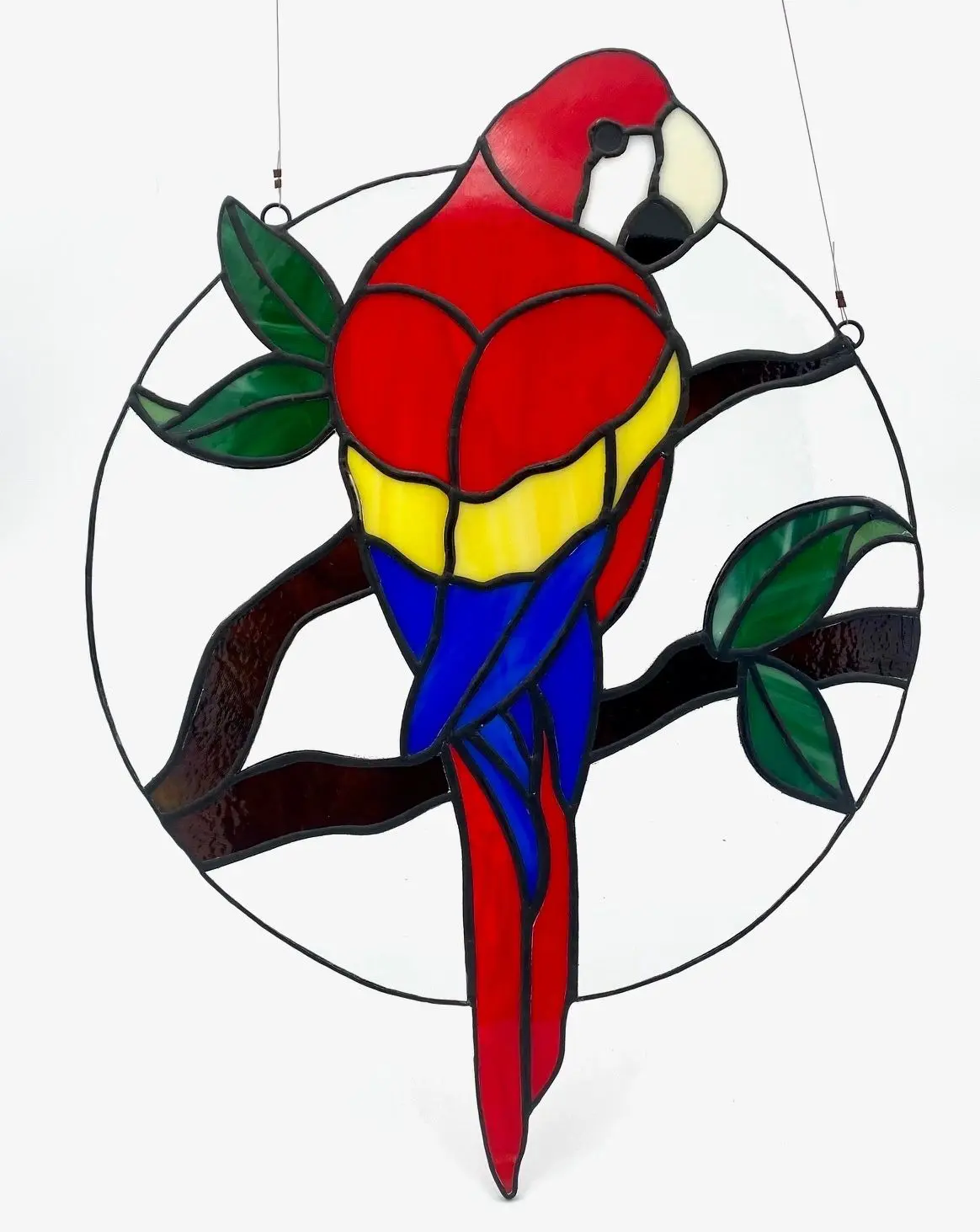 A stained glass parrot sitting on top of a tree branch.