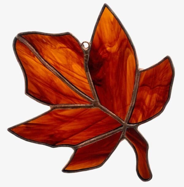 A stained glass leaf hanging on the wall.